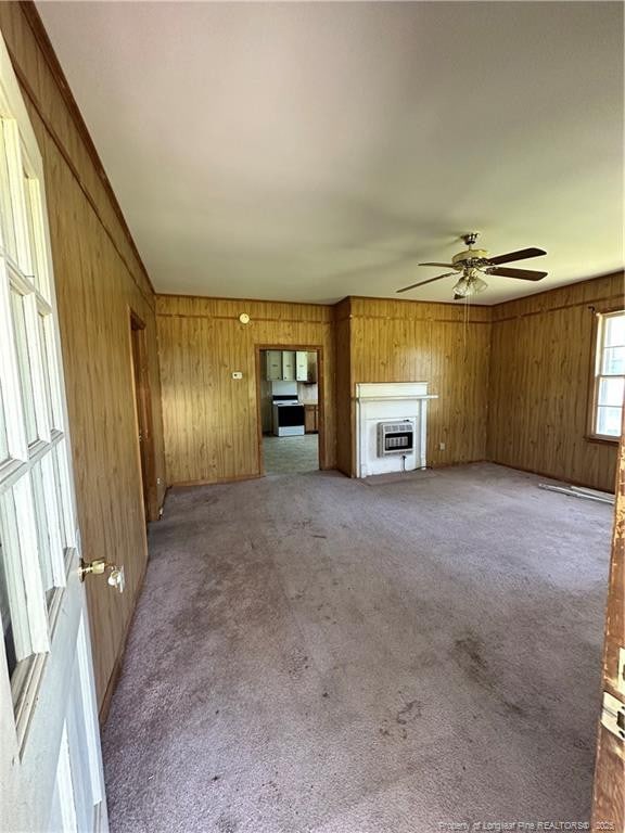 410 W K St, Erwin, NC 28339 - unfurnished living room with a ceiling fan, wood walls, carpet floors, heating unit, and a fireplace