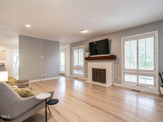 3205 Dell Dr, Raleigh, NC 27609 - living area featuring wood finished floors, a brick fireplace, healthy amount of natural light, and recessed lighting