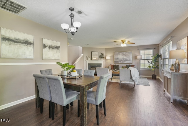211 Cloverdale Dr, Durham, NC 27703 - dining area with a fireplace, dark wood-style flooring, a chandelier, ceiling fan, and a textured ceiling