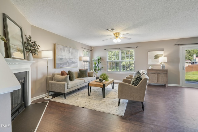 211 Cloverdale Dr, Durham, NC 27703 - living area with a textured ceiling, a fireplace with raised hearth, ceiling fan, and dark wood-type flooring