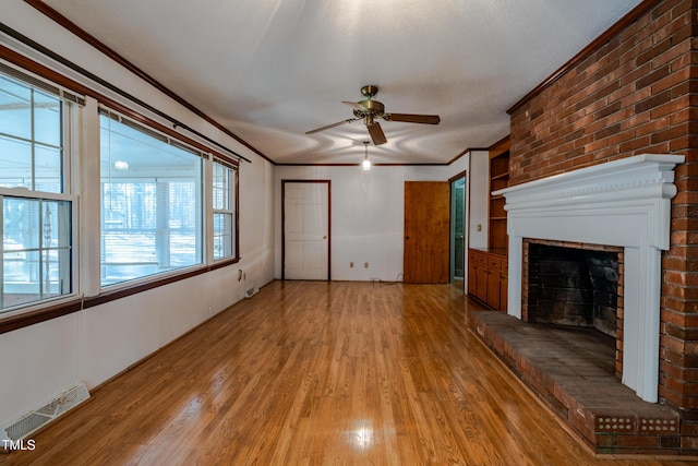 3129 Barwell Rd, Raleigh, NC 27610 - unfurnished living room featuring a ceiling fan, light wood finished floors, a brick fireplace, and crown molding
