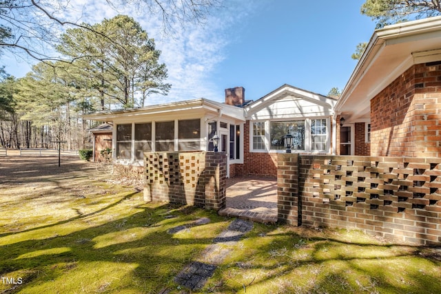 3129 Barwell Rd, Raleigh, NC 27610 - back of property featuring a sunroom, brick siding, and a chimney