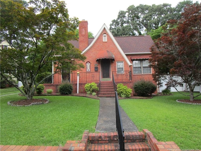 432 Rollingwood Cir, Fayetteville, NC 28305 - tudor house with a chimney, a front yard, brick siding, and roof with shingles
