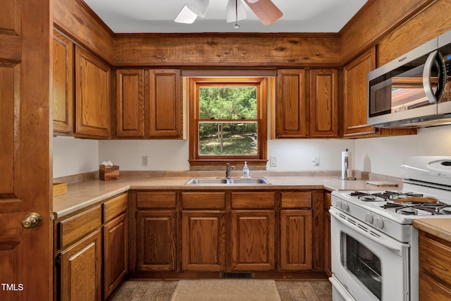 4134 King Charles Rd, Durham, NC 27707 - kitchen with stainless steel microwave, white range with gas stovetop, brown cabinets, light countertops, and ceiling fan