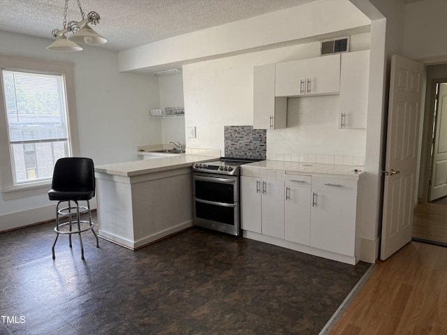 903 New Bern Ave, Raleigh, NC 27601 - kitchen with double oven range, a peninsula, white cabinets, tasteful backsplash, and a textured ceiling
