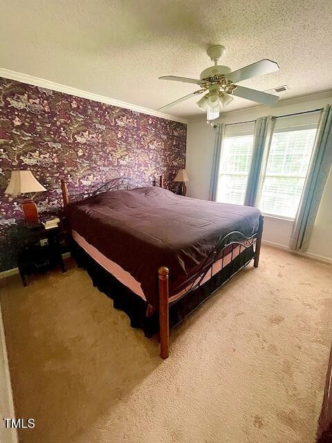 6328 Bermuda Way, Whitsett, NC 27377 - bedroom featuring a textured ceiling, light colored carpet, ceiling fan, and crown molding