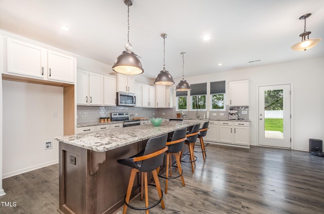 23 Walker Grove Ln, Lillington, NC 27546 - kitchen with appliances with stainless steel finishes, white cabinetry, tasteful backsplash, a center island, and dark wood finished floors