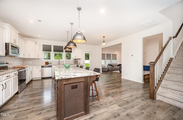 23 Walker Grove Ln, Lillington, NC 27546 - kitchen featuring stainless steel appliances, a breakfast bar, a center island, decorative backsplash, and white cabinetry
