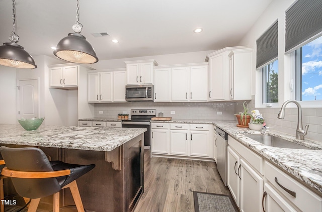 23 Walker Grove Ln, Lillington, NC 27546 - kitchen featuring stainless steel appliances, white cabinetry, tasteful backsplash, decorative light fixtures, and wood finished floors