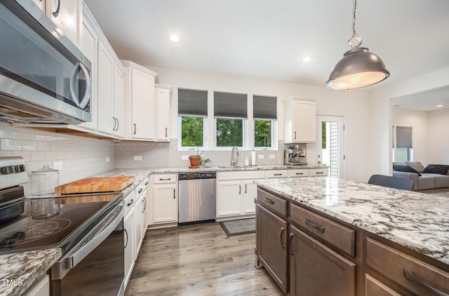 23 Walker Grove Ln, Lillington, NC 27546 - kitchen featuring stainless steel appliances, white cabinets, light wood-type flooring, decorative backsplash, and light stone countertops