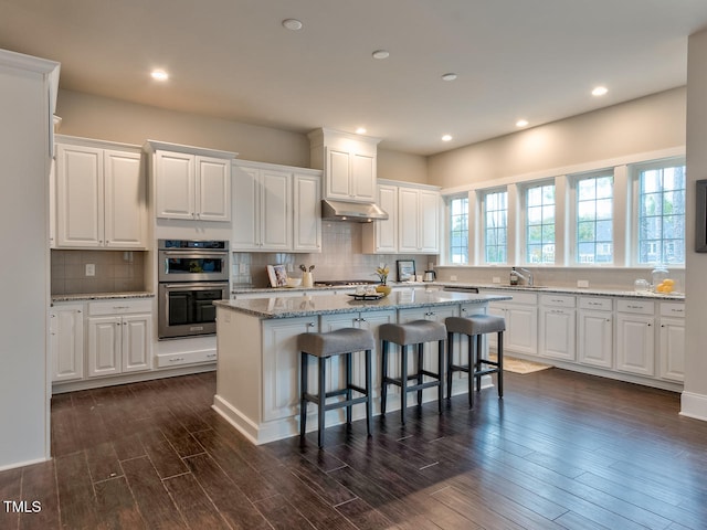 3526 Clifton Park Ct, New Hill, NC 27562 - kitchen with appliances with stainless steel finishes, white cabinets, a center island, a breakfast bar area, and recessed lighting