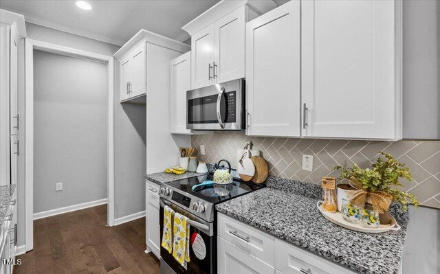 213 Guerrant St, Greensboro, NC 27401 - kitchen featuring appliances with stainless steel finishes, light stone counters, white cabinetry, dark wood-style flooring, and decorative backsplash