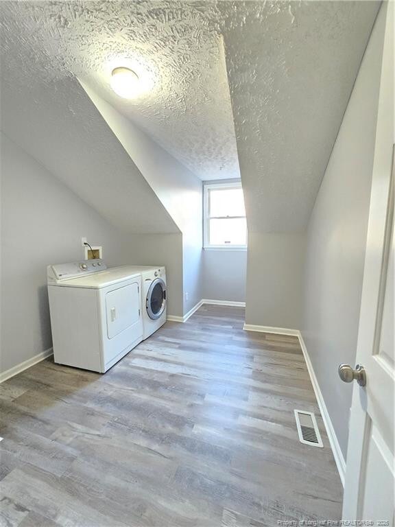1654 Baysden Ct, Fayetteville, NC 28303 - washroom featuring washing machine and clothes dryer, a textured ceiling, and light wood finished floors