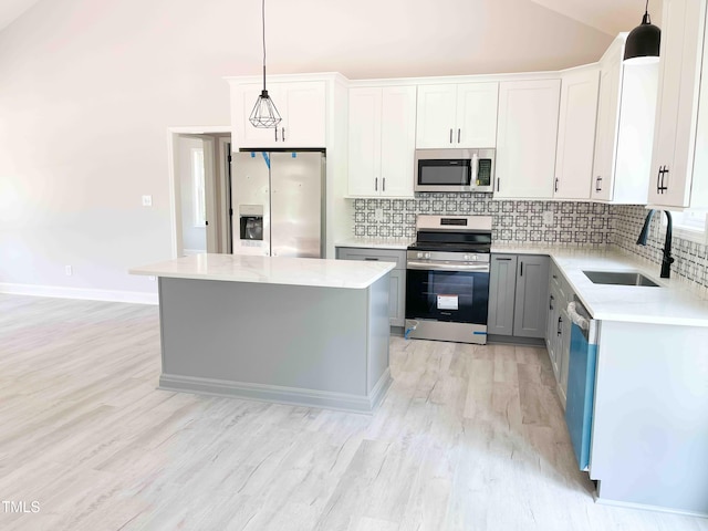 341 Rev Henderson Rd, Henderson, NC 27537 - kitchen featuring stainless steel appliances, vaulted ceiling, decorative backsplash, light wood-type flooring, and light countertops