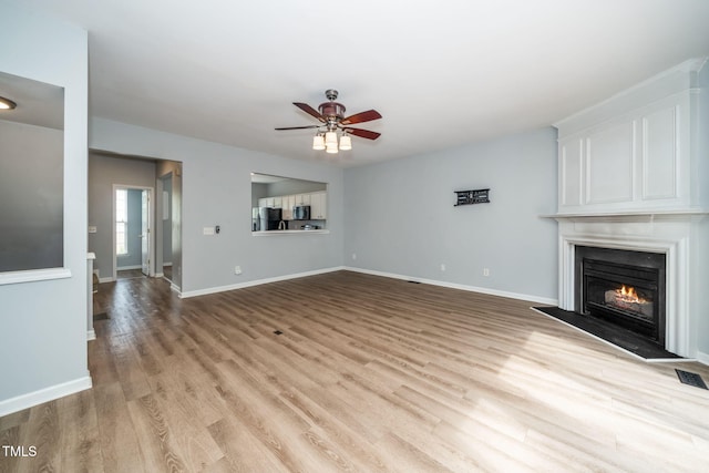7226 Corvette Ct, Raleigh, NC 27613 - unfurnished living room featuring light wood-type flooring, ceiling fan, and a lit fireplace