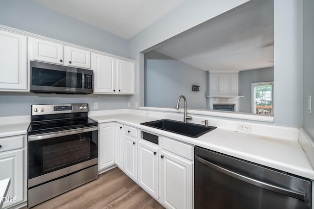 7226 Corvette Ct, Raleigh, NC 27613 - kitchen featuring appliances with stainless steel finishes, white cabinets, light countertops, and light wood-type flooring