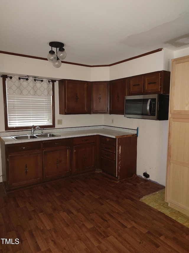 1161 Morgan Rd, Henderson, NC 27537 - kitchen with stainless steel microwave, dark wood-type flooring, light countertops, dark brown cabinets, and ornamental molding