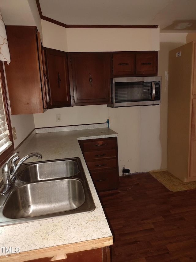 1161 Morgan Rd, Henderson, NC 27537 - kitchen with stainless steel microwave, wood finished floors, light countertops, dark brown cabinetry, and ornamental molding