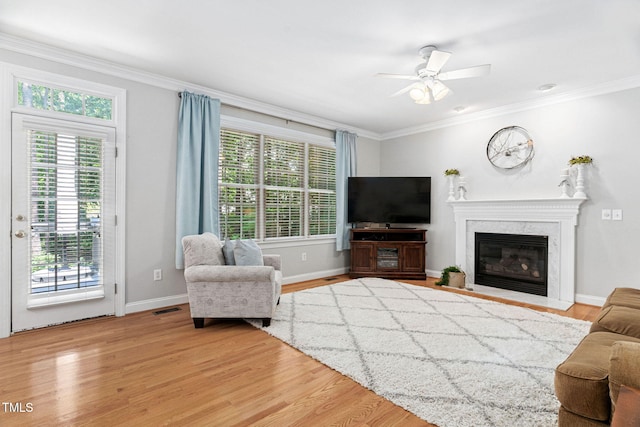 2608 Forestbluff Dr, Fuquay Varina, NC 27526 - living room featuring healthy amount of natural light, ornamental molding, light wood-style floors, ceiling fan, and a premium fireplace