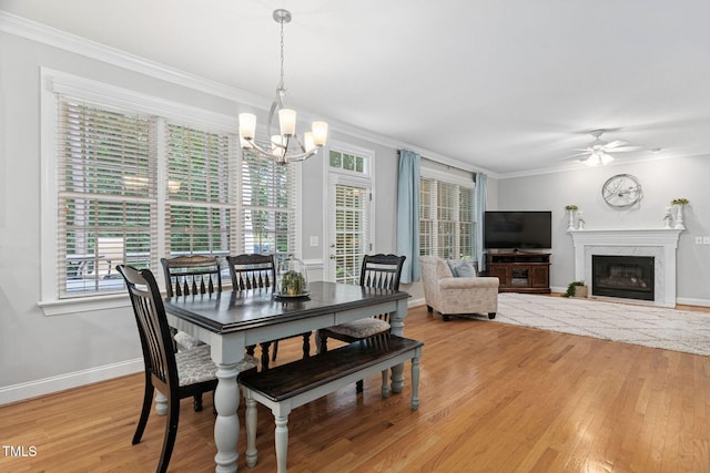 2608 Forestbluff Dr, Fuquay Varina, NC 27526 - dining area with a chandelier, light wood-style flooring, crown molding, healthy amount of natural light, and a high end fireplace