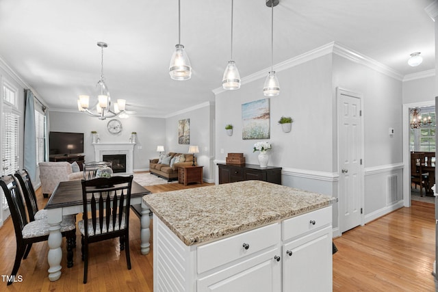 2608 Forestbluff Dr, Fuquay Varina, NC 27526 - kitchen with a chandelier, light wood-type flooring, crown molding, a fireplace, and white cabinetry