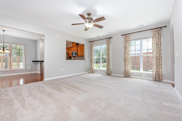 732 Hornchurch Loop, Cary, NC 27519 - unfurnished living room with light colored carpet, a chandelier, and ceiling fan