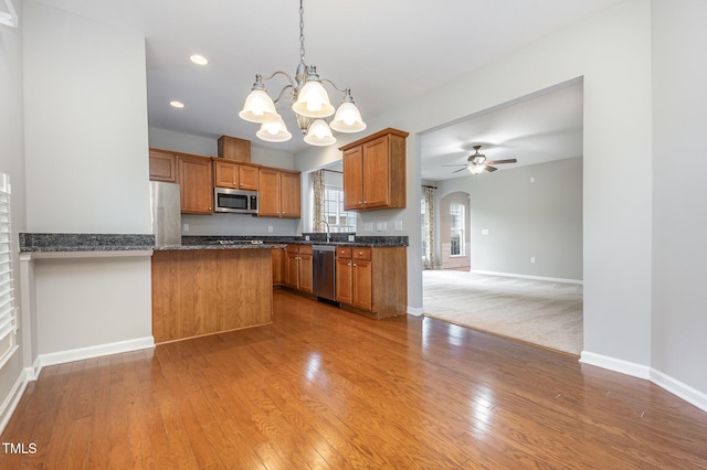732 Hornchurch Loop, Cary, NC 27519 - kitchen featuring stainless steel appliances, a ceiling fan, brown cabinetry, a chandelier, and a peninsula