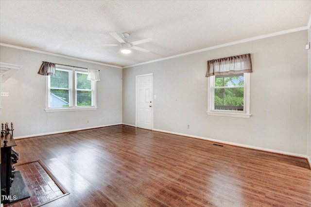 607 E Geer St, Durham, NC 27701 - unfurnished living room featuring healthy amount of natural light, wood finished floors, a ceiling fan, ornamental molding, and a wood stove