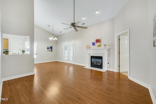 325 Millet Dr, Morrisville, NC 27560 - unfurnished living room with high vaulted ceiling, a fireplace, ceiling fan, wood finished floors, and a chandelier