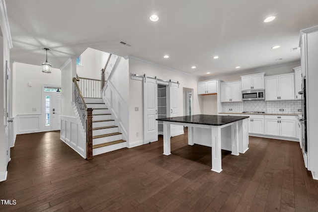 211 Camille Cir, Youngsville, NC 27596 - kitchen with appliances with stainless steel finishes, white cabinets, a barn door, dark wood finished floors, and wainscoting