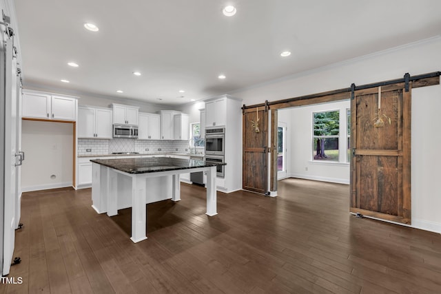 211 Camille Cir, Youngsville, NC 27596 - kitchen with stainless steel appliances, a barn door, a breakfast bar, white cabinetry, and decorative backsplash