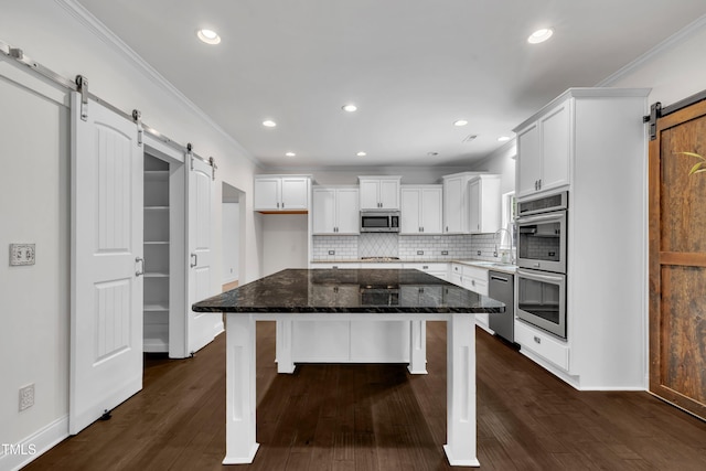 211 Camille Cir, Youngsville, NC 27596 - kitchen featuring a barn door, appliances with stainless steel finishes, crown molding, white cabinetry, and backsplash