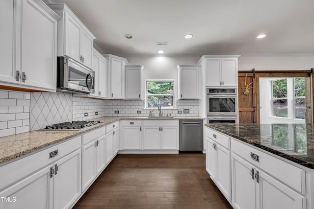 211 Camille Cir, Youngsville, NC 27596 - kitchen with appliances with stainless steel finishes, white cabinetry, dark wood-style floors, dark stone countertops, and crown molding