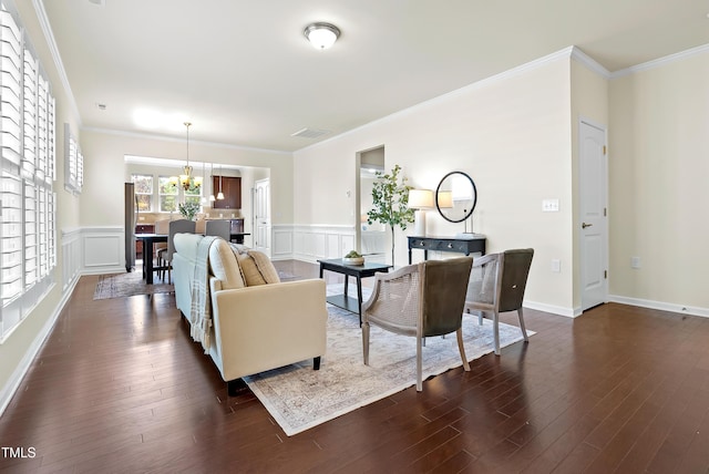 325 Currituck Ln, Durham, NC 27703 - living room with a chandelier, wainscoting, dark wood finished floors, ornamental molding, and a decorative wall