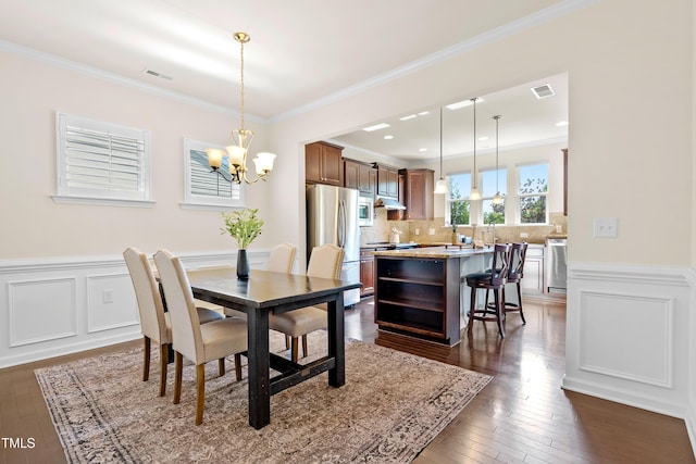 325 Currituck Ln, Durham, NC 27703 - dining space featuring a chandelier, dark wood finished floors, crown molding, a wainscoted wall, and a decorative wall