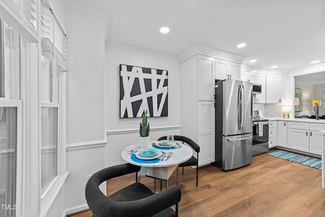 1035 High Lake Ct, Raleigh, NC 27606 - kitchen with stainless steel appliances, white cabinetry, light wood-style floors, crown molding, and light countertops