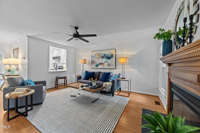 1035 High Lake Ct, Raleigh, NC 27606 - living area featuring a fireplace with flush hearth, ornamental molding, a ceiling fan, and wood finished floors