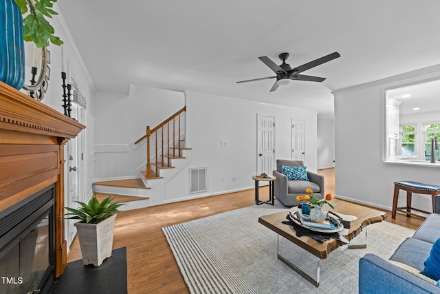 1035 High Lake Ct, Raleigh, NC 27606 - living area with stairway, wood finished floors, crown molding, a fireplace with flush hearth, and ceiling fan