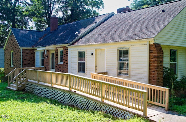 2001 Thomas Ln, Henderson, NC 27536 - back of property featuring brick siding, a chimney, a deck, a yard, and roof with shingles