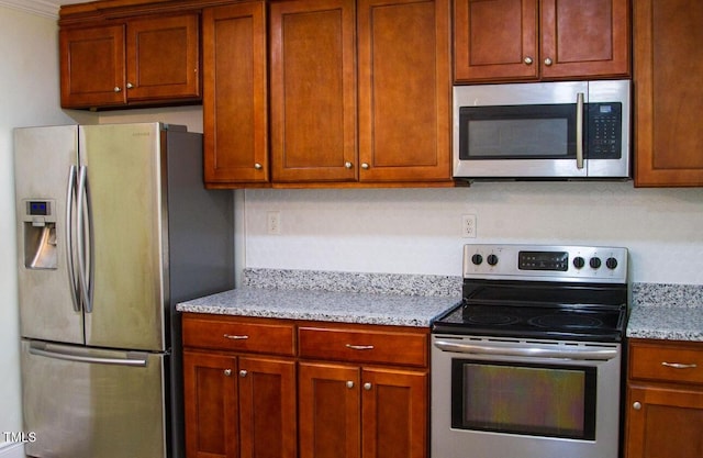 2001 Thomas Ln, Henderson, NC 27536 - kitchen featuring appliances with stainless steel finishes, light stone counters, brown cabinets, and ornamental molding