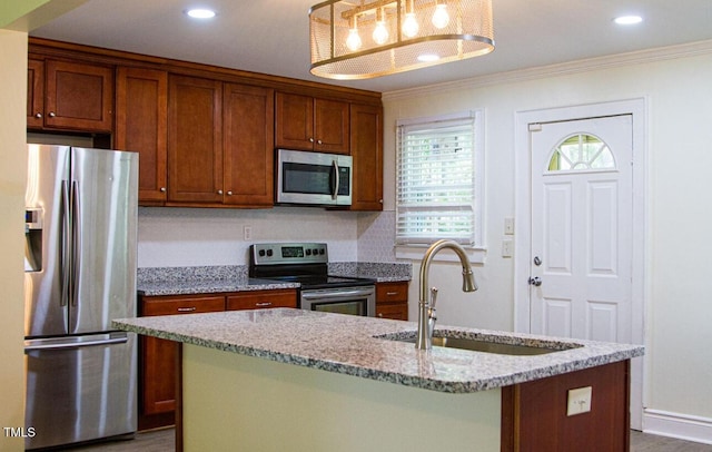 2001 Thomas Ln, Henderson, NC 27536 - kitchen with stainless steel appliances, ornamental molding, brown cabinetry, a kitchen island with sink, and light stone counters