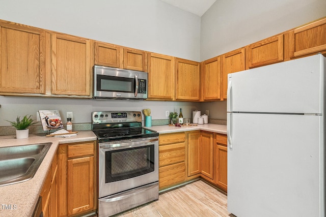 3050 Trailwood Pines Ln Unit 303, Raleigh, NC 27603 - kitchen with appliances with stainless steel finishes, light countertops, light wood finished floors, and brown cabinetry