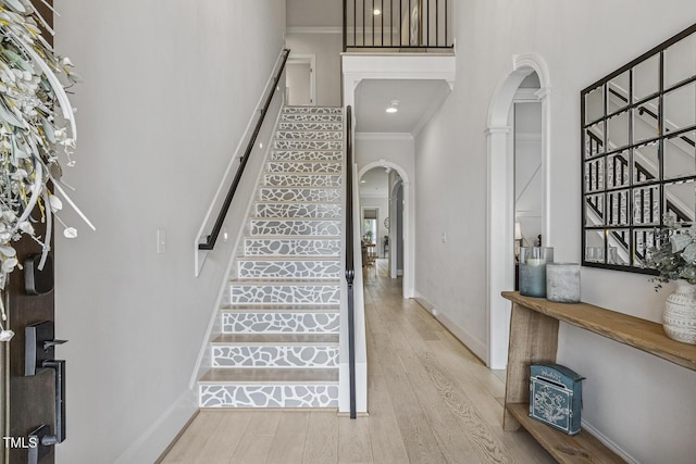 2098 Amalfi Pl, Apex, NC 27502 - foyer entrance featuring arched walkways, light wood finished floors, stairs, ornamental molding, and a towering ceiling