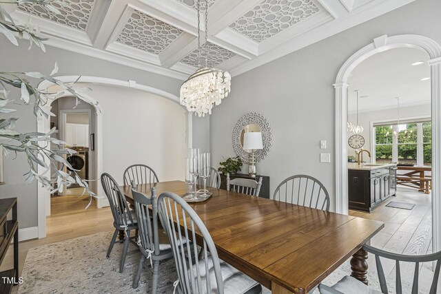 2098 Amalfi Pl, Apex, NC 27502 - dining room featuring a chandelier, arched walkways, light wood-type flooring, beam ceiling, and washer / dryer