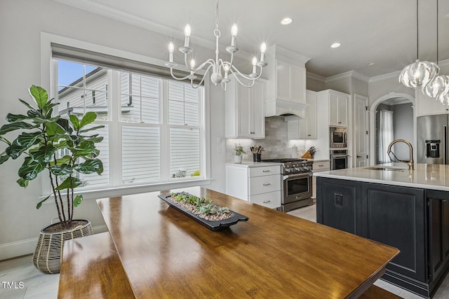 2098 Amalfi Pl, Apex, NC 27502 - kitchen with stainless steel appliances, a chandelier, white cabinets, tasteful backsplash, and arched walkways