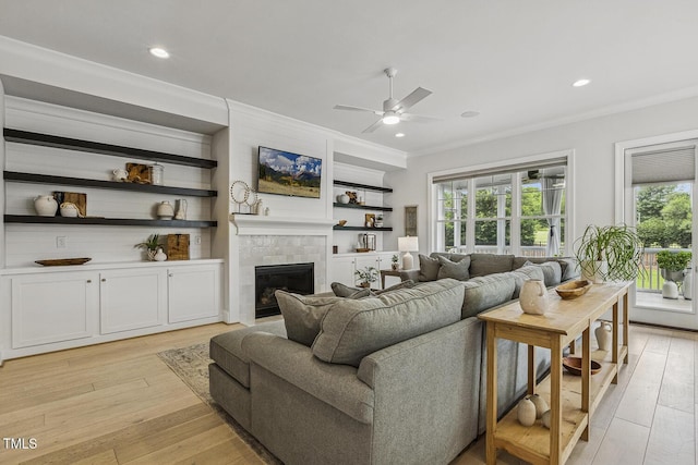 2098 Amalfi Pl, Apex, NC 27502 - living room featuring ceiling fan, plenty of natural light, a tile fireplace, light wood-style floors, and crown molding