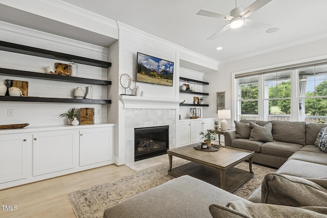 2098 Amalfi Pl, Apex, NC 27502 - living area featuring light wood-style floors, ceiling fan, a tiled fireplace, ornamental molding, and recessed lighting