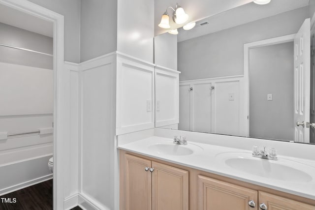 614 Park York Ln, Cary, NC 27519 - full bathroom featuring double vanity, a decorative wall, wainscoting, and wood finished floors