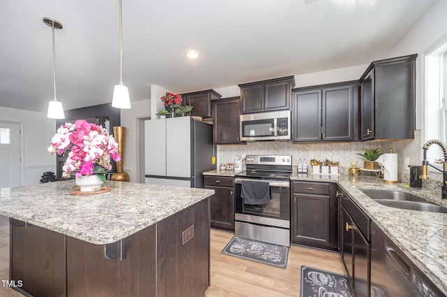 1405 Currituck Ave, Dunn, NC 28334 - kitchen with stainless steel appliances, light wood finished floors, a center island, decorative backsplash, and light stone countertops