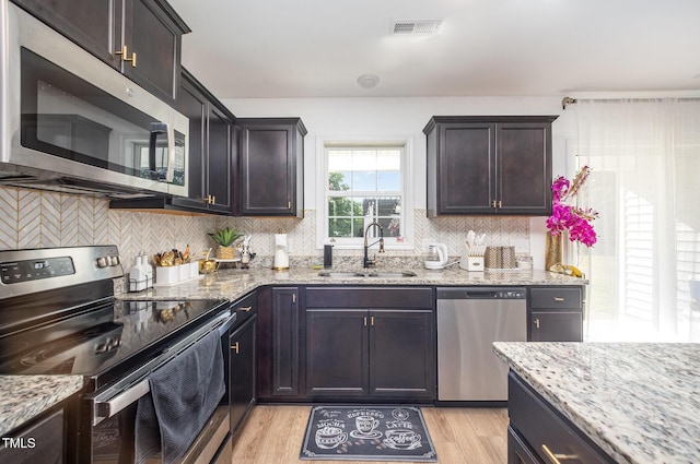 1405 Currituck Ave, Dunn, NC 28334 - kitchen with stainless steel appliances, light wood-type flooring, backsplash, light stone countertops, and dark brown cabinetry